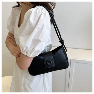 Detail of black matte underarm bag with unique circular buckle and knotted strap