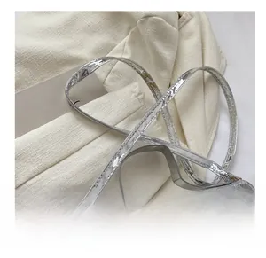 Detail van zilveren crossbodytas met slangenpatroon en verstelbare schouderband