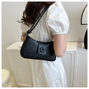 Chic black underarm bag with knot detail and magnetic closure shown on a white dress