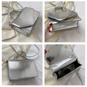 Detail van de zilveren handtas met krokodillenreliëf toont binnenkant en magneetsluiting
