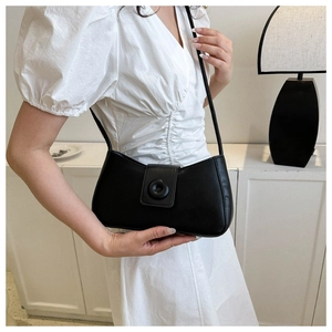 Chic black underarm bag with a round buckle detail shown on a white pleated dress