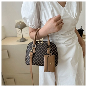 Dettaglio della borsa vintage con stampa geometrica e manico in pelle su abito bianco