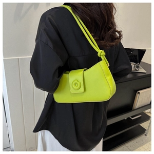 Detail view of lime green leather underarm bag with knot strap and round buckle