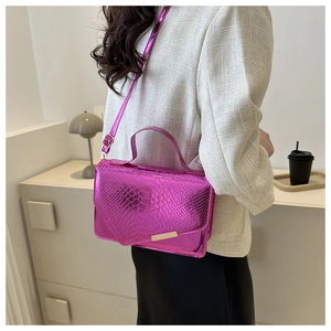 Detail van fuchsia crossbodytas met slangenpatroon en glanzende metalen afwerking
