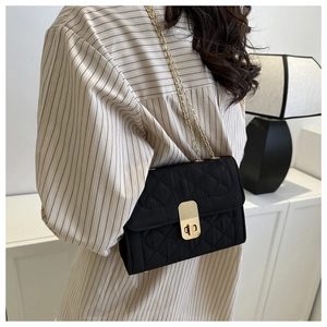 Detail of black quilted crossbody bag with gold chain strap and metallic twist lock clasp