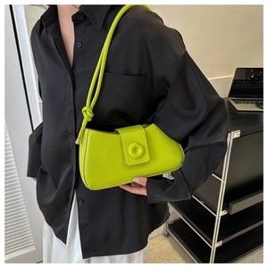 Detail of neon green baguette bag with knotted strap and floral magnetic buckle on shoulder