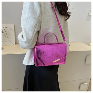 Model met een metallic rozerode handtas met krokodillentextuur en gouden sluiting