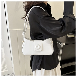Detail of white glossy underarm bag with unique flap closure and side knot strap detail