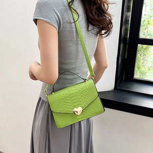 Bright green crocodile pattern crossbody bag with a golden heart clasp on a model