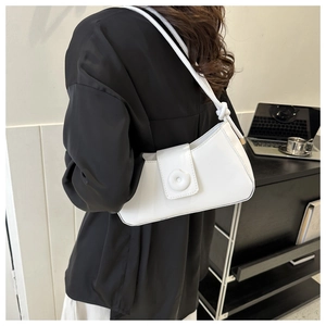 Close-up of white underarm bag featuring a unique knot handle and matte leather texture