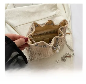 Détail intérieur du sac seau en paille avec espace pour téléphone, portefeuille et chaîne