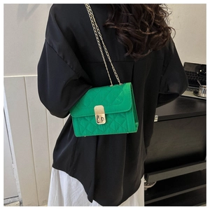 Detail of green quilted crossbody bag with gold chain strap and turn-lock closure