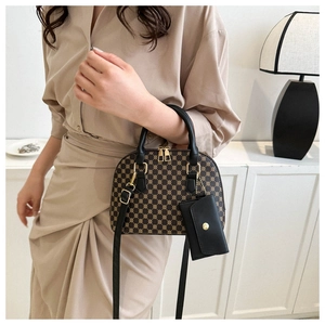 Borsa a mano con stampa monogramma e manico nero mostrata in un ambiente moderno chic