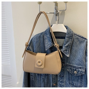 Detail of beige crescent underarm bag with unique knotted strap and gold metal tips