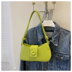 Detail of neon green baguette bag shoulder strap knot and smooth synthetic leather