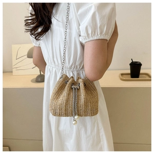 Détail du sac seau en paille avec chaîne argentée et cordon à perles décoratives