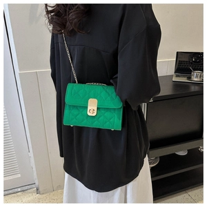 Detail of vibrant green quilted crossbody bag with gold chain strap and metal lock