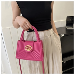 Detail van een roze geplooide crossbodytas met een gouden hartslot en verfijnd stiksel