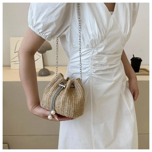 Détail du sac seau en paille avec cordon en chaîne argentée et grandes perles blanches