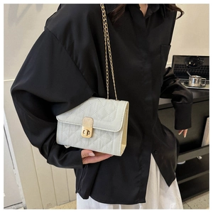 Detail of white quilted crossbody bag with gold chain strap and metallic twist lock