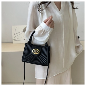 Detail van zwarte geplooide crossbodytas met ronde stiksels en gouden gesp op een model