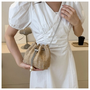 Détail du sac seau en paille avec perles de serrage et bandoulière chaîne