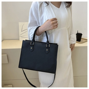 Detail of black faux leather tote bag with round handles and detachable strap on model
