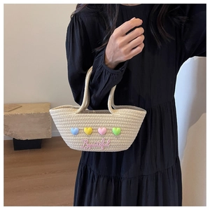 Detail van handgeweven touwtas met pastelkleurige 3D-harten en mooie tekstpatch