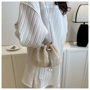 Détail du sac seau en paille avec tissage en V, chaîne argentée et perles de serrage