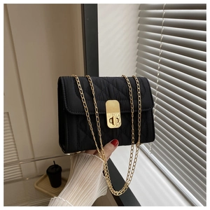 Detail of a black quilted crossbody bag with a gold chain strap and metallic twist lock