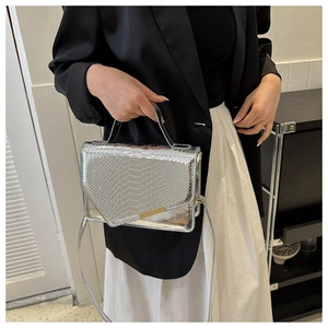 Detail van zilveren handtas met slangenpatroon, metalen slot en slanke schouderriem