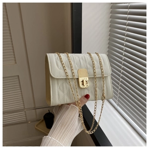 Close-up of white quilted crossbody bag with gold metal chain and rectangular buckle