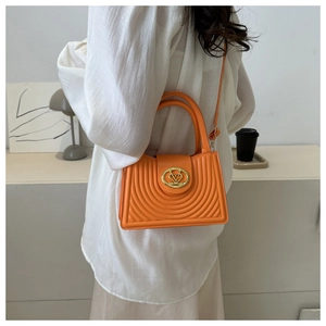 Detailopname van feloranje gewatteerde tas met goudkleurige hartgesp op het model