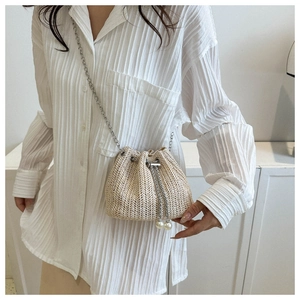 Détails du sac seau en paille tressée avec bandoulière chaîne et perles décoratives