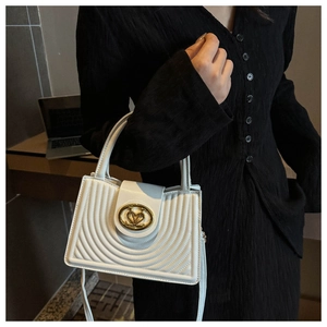 Detail van witte crossbodytas met gewatteerde stiksels en gouden hart-draaisluiting