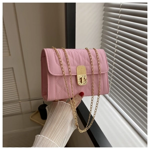 Close-up of pink quilted crossbody bag with golden chain strap and twist lock detail