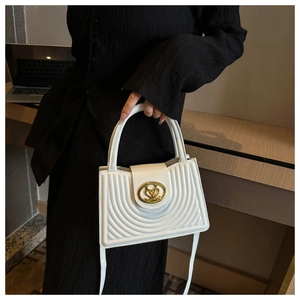 Detail van witte gewatteerde handtas met hartvormige gouden gesp en luxe stiksels