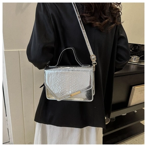 Detail van zilveren crossbodytas met krokodillenpatroon en glanzende afwerking