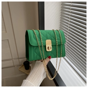 Detail of green quilted crossbody bag showing gold metal chain and rectangular twist lock