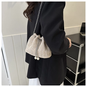 Détail du sac seau en paille avec perles de serrage et bandoulière en chaîne