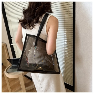 Close-up of transparent black PVC tote bag with colorful rhinestones and leather straps