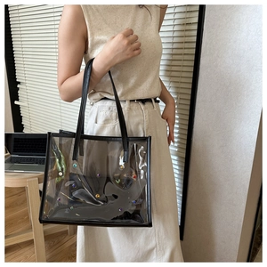 Close-up of clear PVC tote bag with colorful studs and black leather shoulder straps