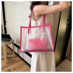 Detailed view of clear PVC tote with pink trim and colorful rhinestone studs with inner pouch