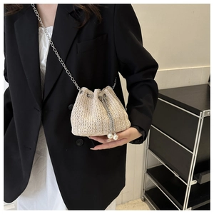 Détail du sac seau tissé crème avec cordon en perles et bandoulière chaîne argent