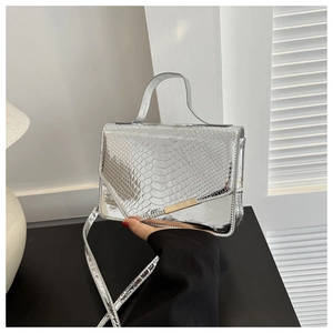Detailopname van de zilveren handtas met slangenleerreliëf en goudkleurige metalen accenten