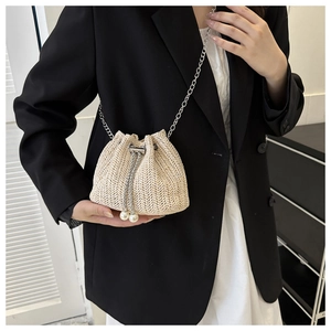 Détail du sac seau en paille beige avec breloques perles et bandoulière chaîne