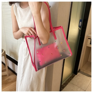 Detailed shot of transparent PVC tote bag with pink trim and colorful rhinestones