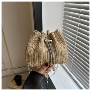 Détail du sac seau en paille avec cordon de serrage, perles et bandoulière chaîne