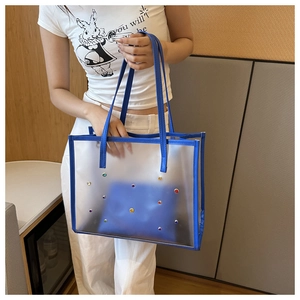 Detailed side view of clear PVC tote bag with blue trim and colorful rhinestone accents