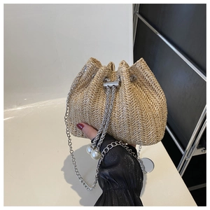 Détail du sac seau en paille avec chaîne argentée et cordon à breloque perle